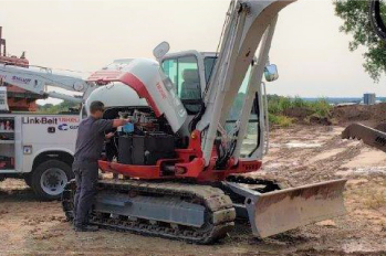 Technician completing field service on an excavator