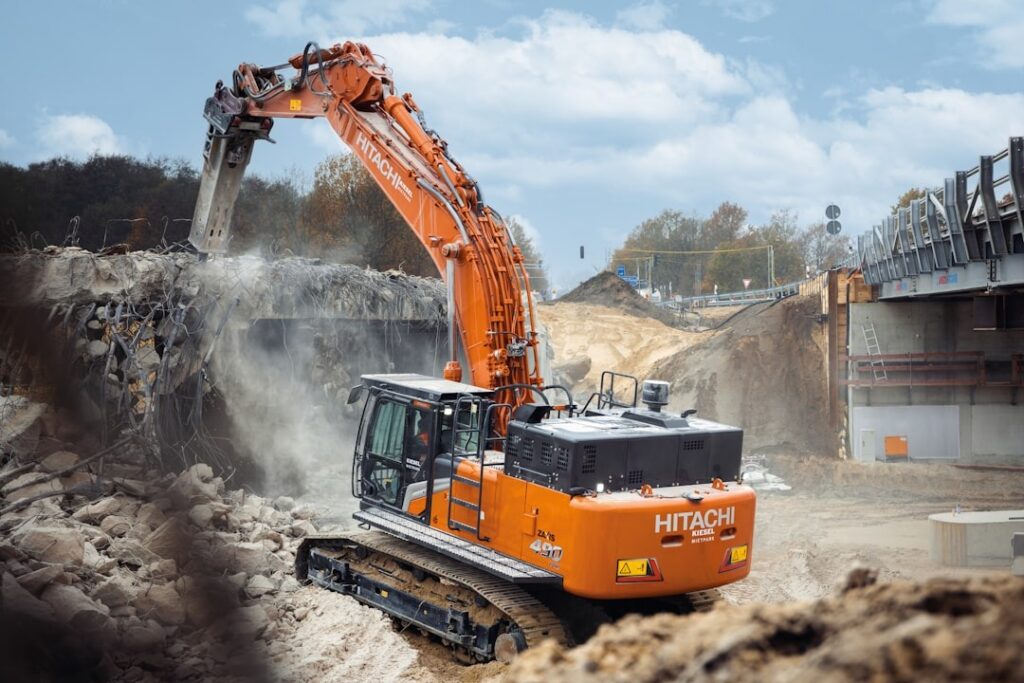 A CONTRACTOR STANDING BETWEEN A NEW HITACHI EXCAVATOR AND A NEW HOLLAND DOZER, MAKING A DECISION - CONSTRUCTION EQUIPMENT LEASE
