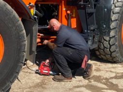A technician checking under a Hitachi/Landcros wheel loader