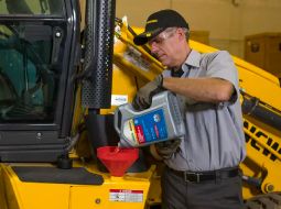 A technician pouring engine oil into a machine