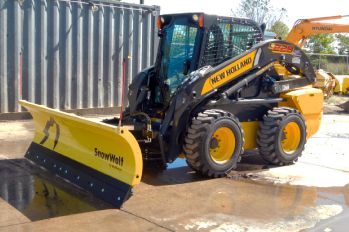 A New Holland skid steer with a yellow SnowWolf blade on wet pavement